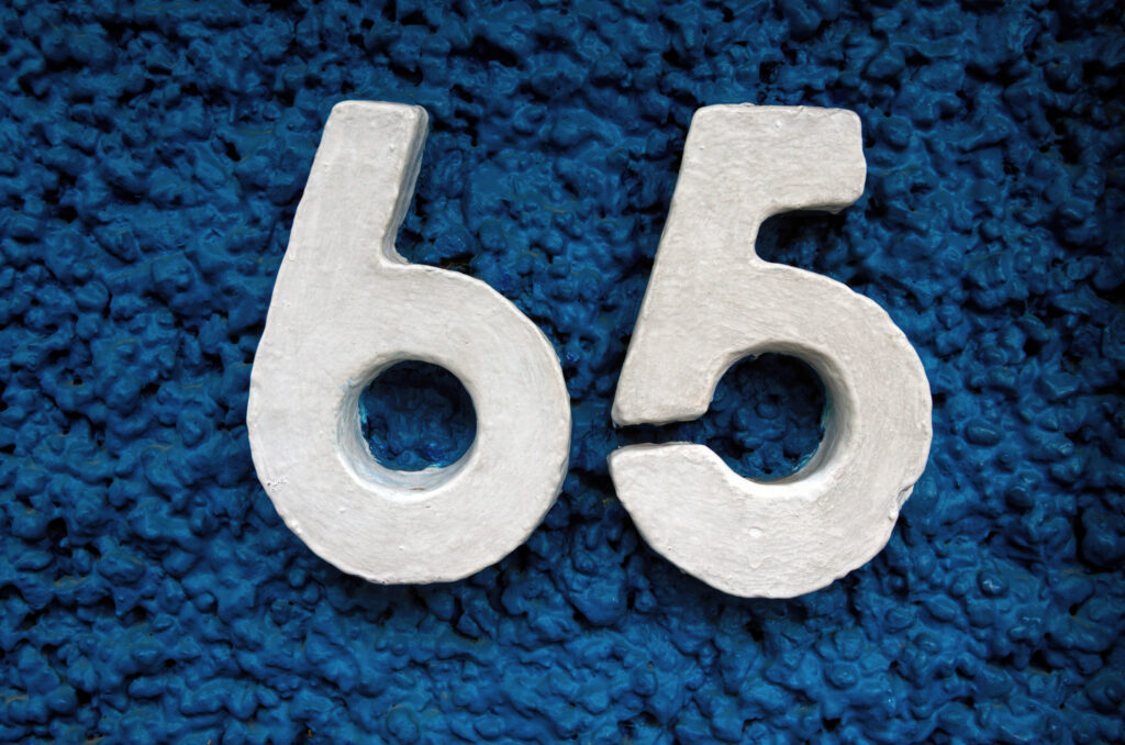 Raised number 65 house address on a building exterior.
