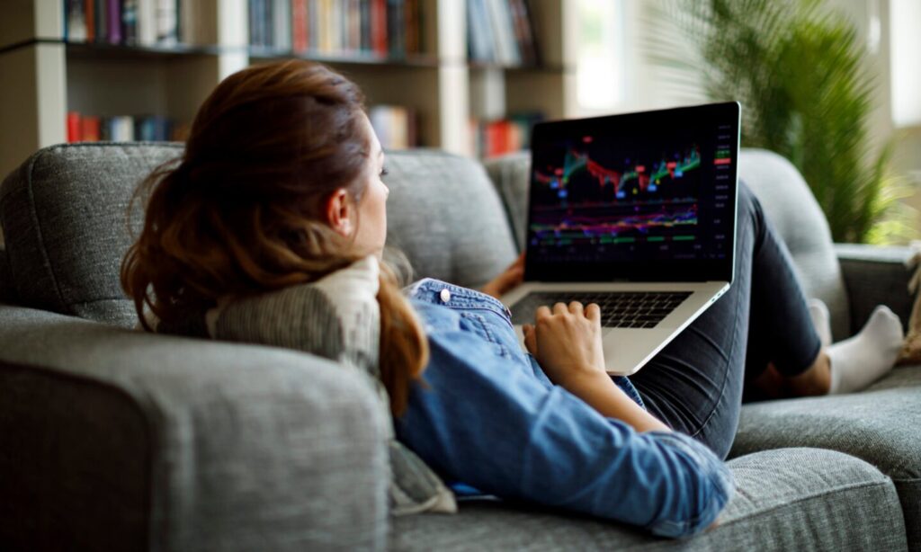 Person on couch looking at stock chart on laptop
