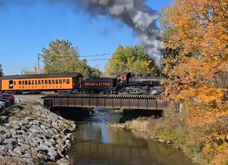 The Arcade &amp; Attica steam train crossing a bridge in fall.