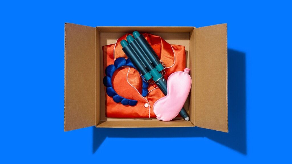 A box filled with PJs, sleep mask and other items on a blue background.