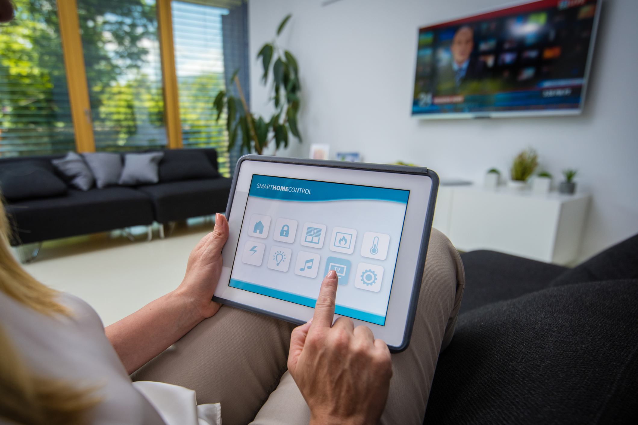 A woman controlling home utilities with a tablet.