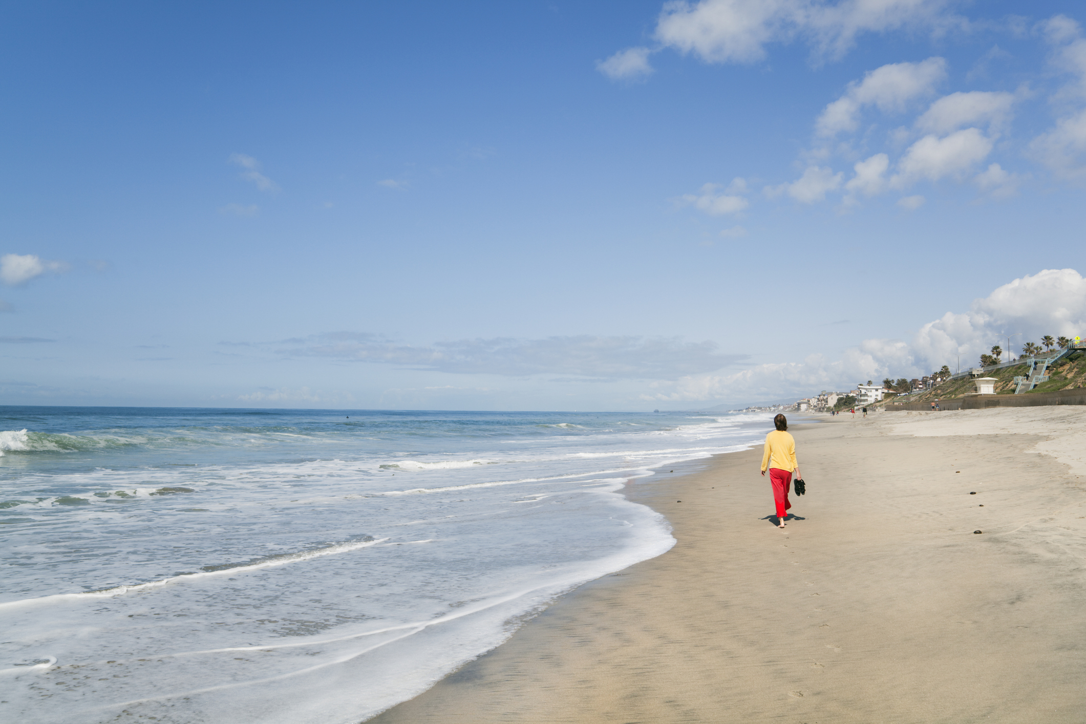 A woman walking along the beach near San Diego