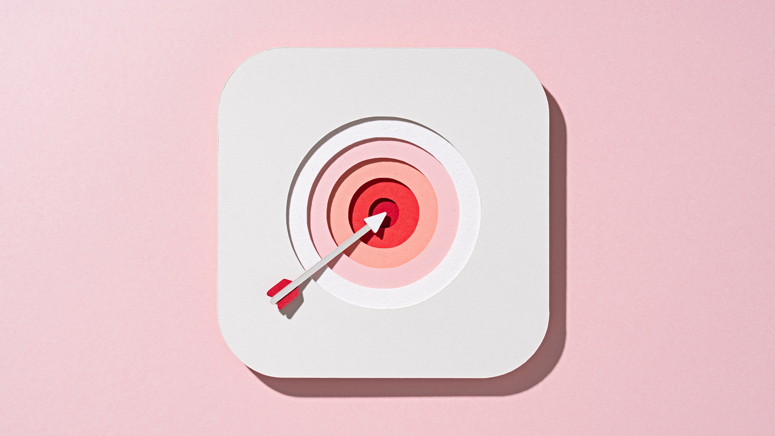An arrow with its tip pointing at a bull's-eye against a pink background.