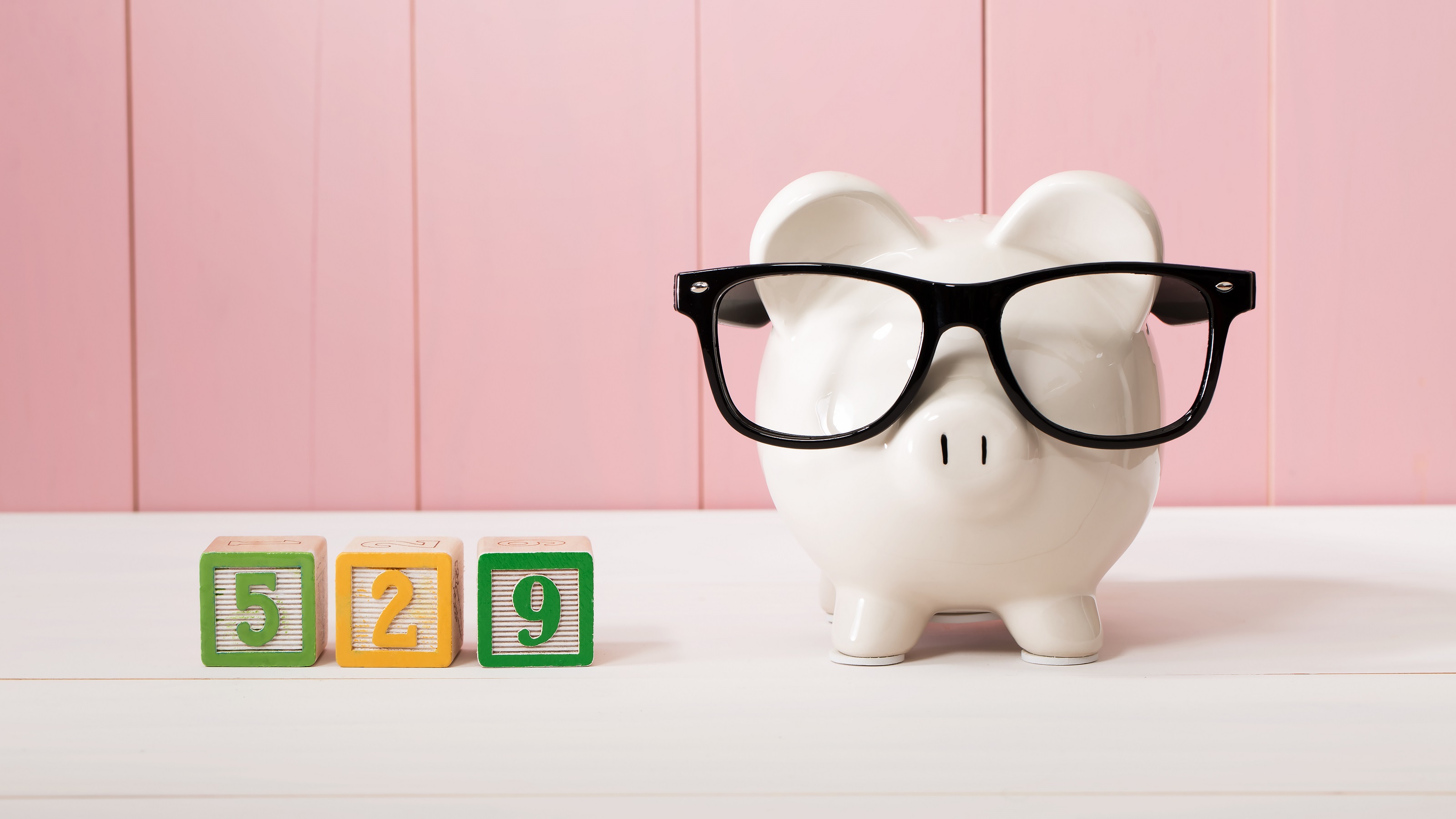 Blocks that say 529 are arranged next to a piggy bank wearing glasses.