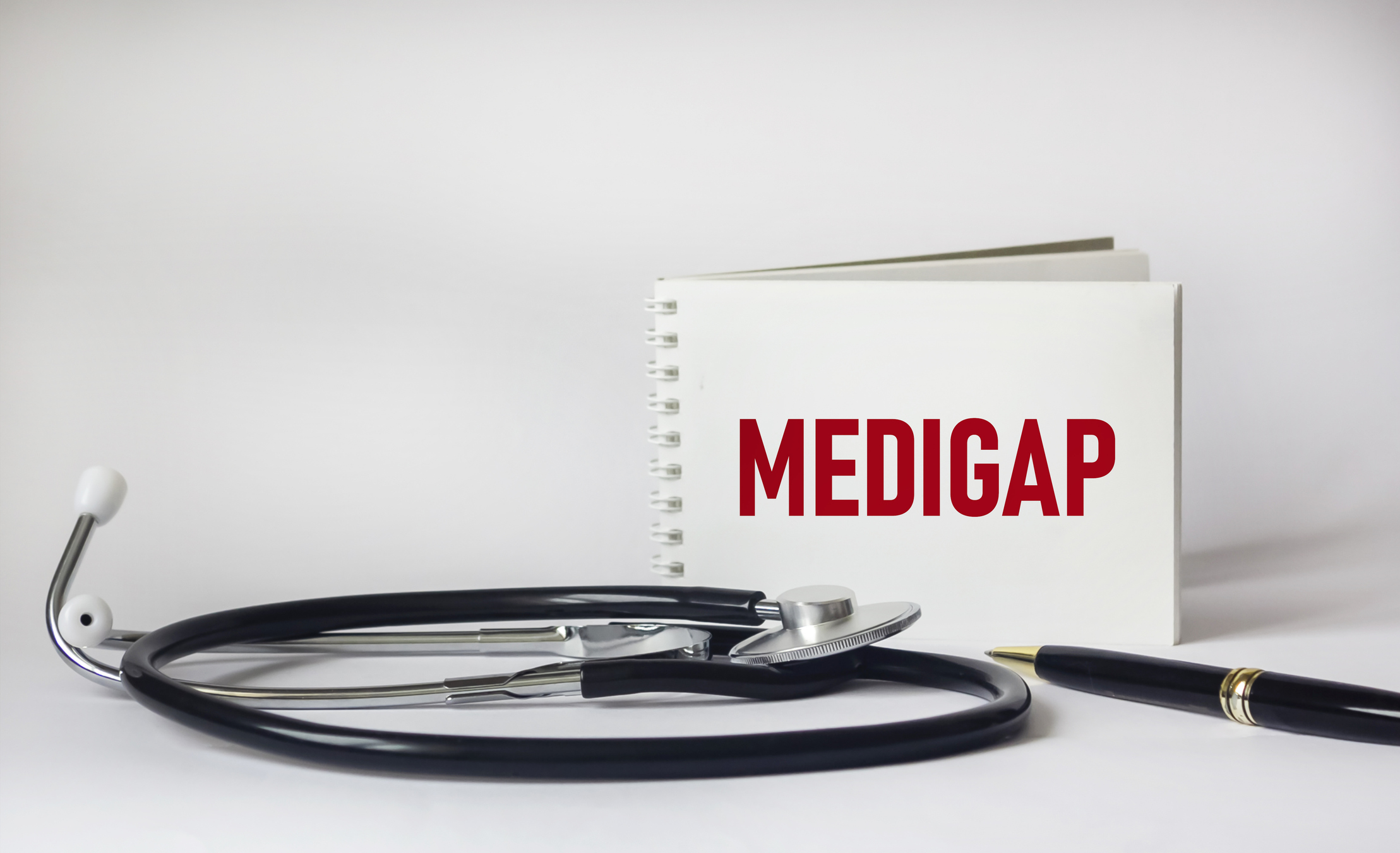 Medigap word on notepad, stethoscope and white background