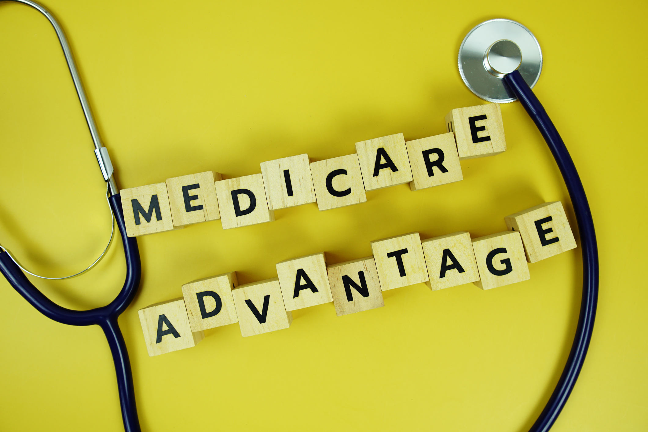 Medicare Advantage with wooden blocks alphabet letters and stethoscope on yellow background