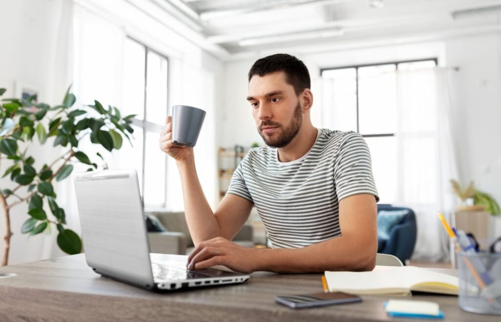 An investor drinking coffee while using a laptop computer.