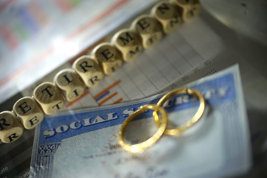 Wedding rings on a Social Security card, next to blocks spelling Retirement.