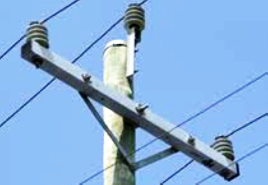 Upper part of an electric transmission utility pole showing wires and various hardware.