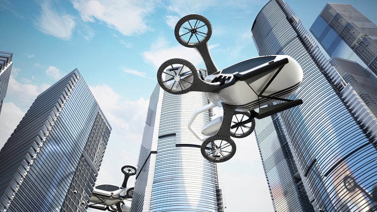 A pair of electric vertical takeoff and landing aircraft fly past skyscrapers.