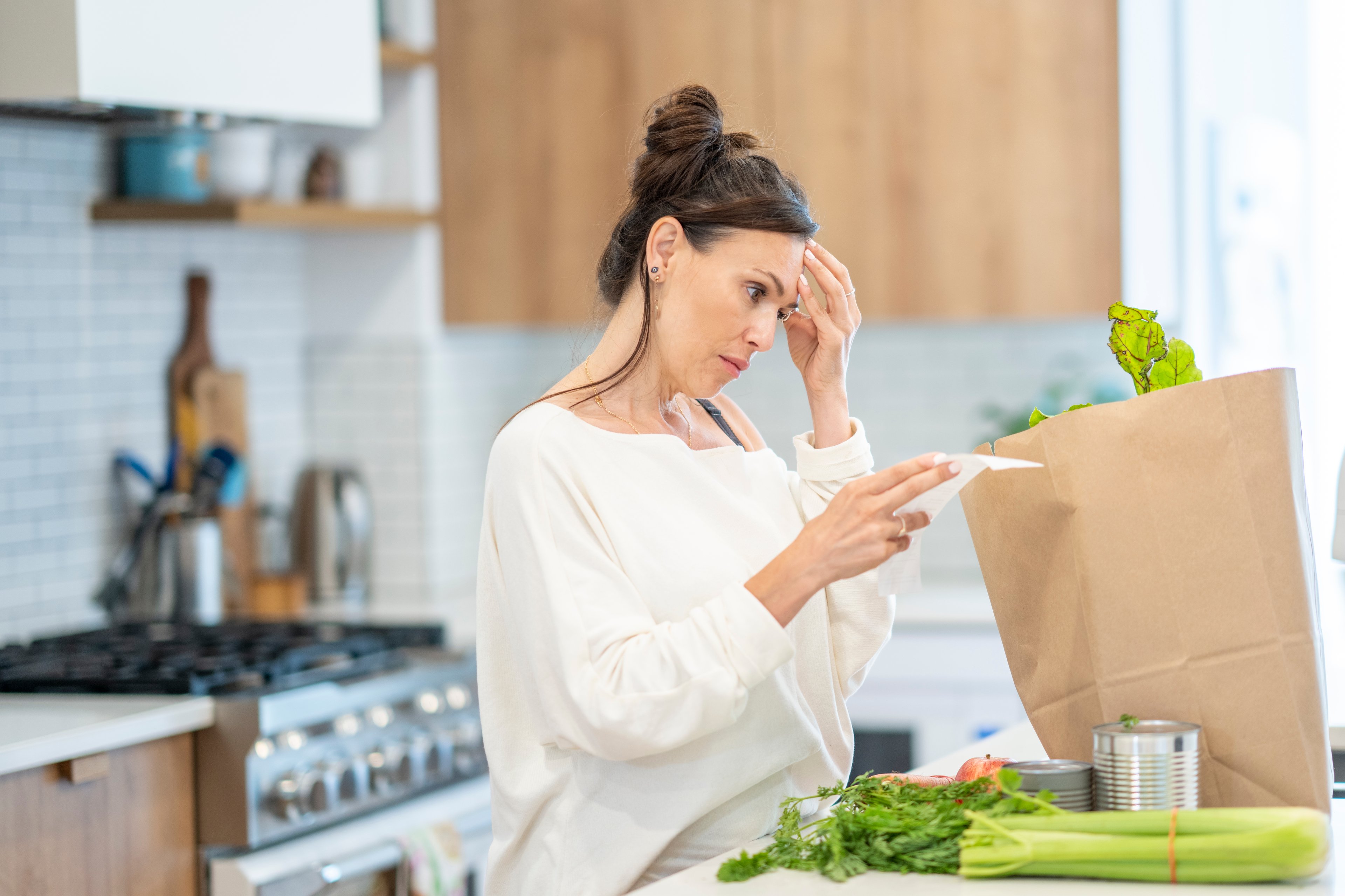 A person in a kitchen looking at a grocery list.