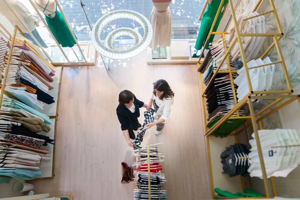 Overhead view of person in clothing store, talking to a store associate.