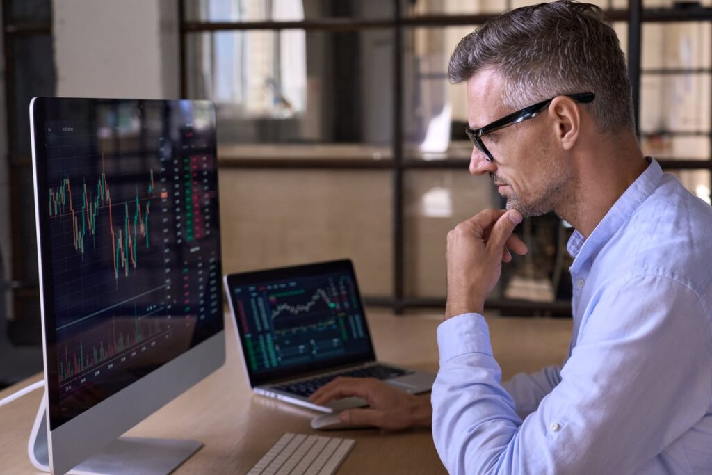 Man looking at financial chart on a screen.