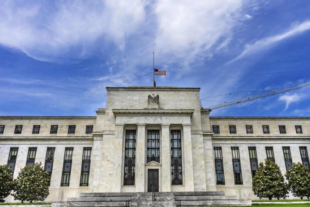Front view of the Federal Reserve headquarters building in Washington, D.C., under a bright blue sky. This image represents the recent report from the Federal Reserve Bank of Philadelphia analyzing the impact of upcoming 2026 graduate student loan caps, which could leave nearly one in three borrowers facing a funding gap. Source: The College Investor