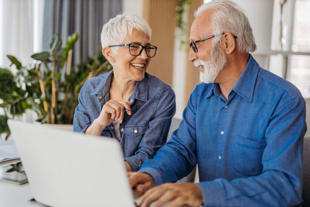 Two smiling people at a laptop.