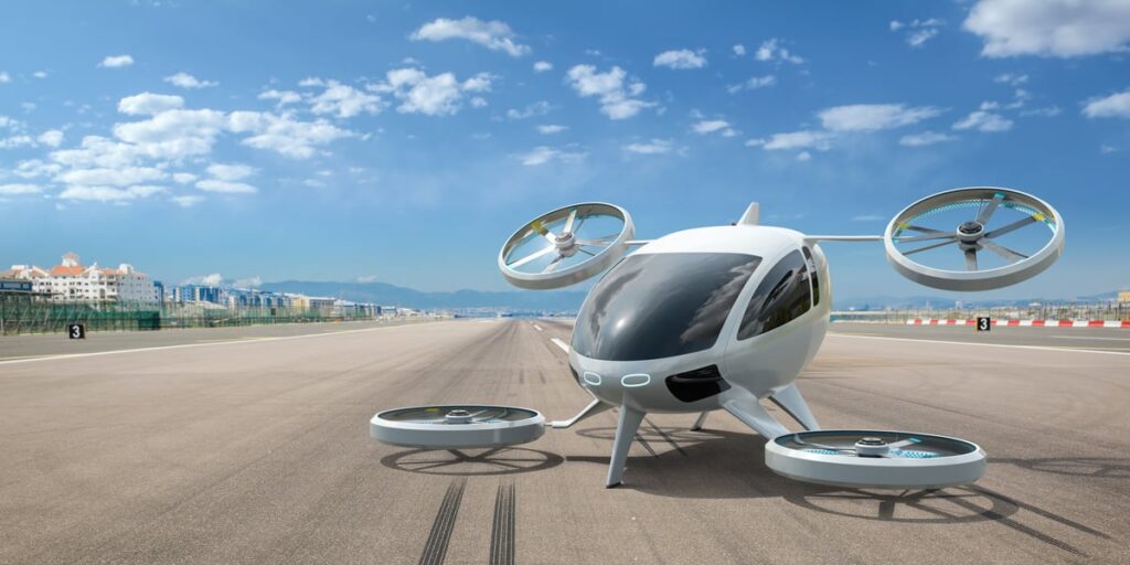 An electric vertical takeoff and landing (eVTOL) aircraft sits on the runway of an urban airport.