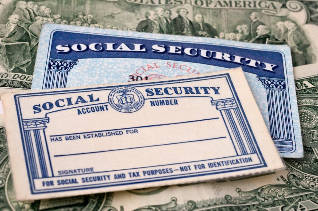 Cash with two Social Security cards placed on top.