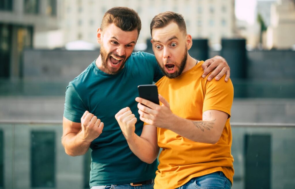 A couple looking at a phone and acting excited.