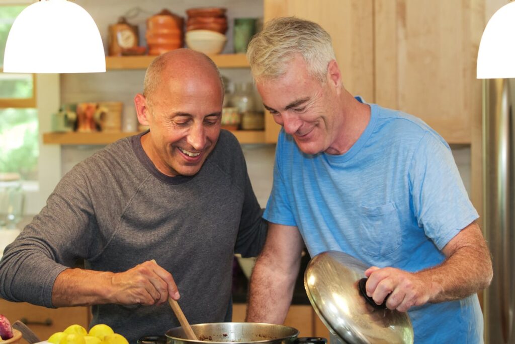 Two people smile as they cook at home.
