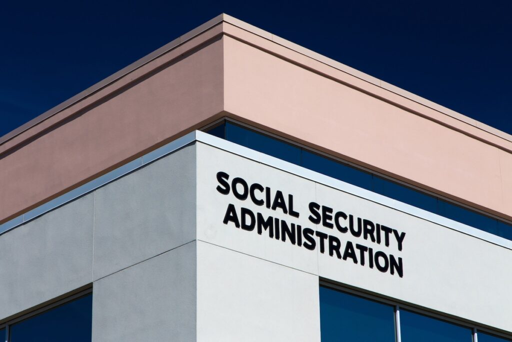 Exterior view of the Social Security Administration building with bold black signage on the facade. This image represents the structural financial challenges facing the program, including a projected trust fund depletion by 2033, which could result in benefit cuts if Congress does not enact reforms such as adjusting payroll taxes or retirement age. Source: The College Investor