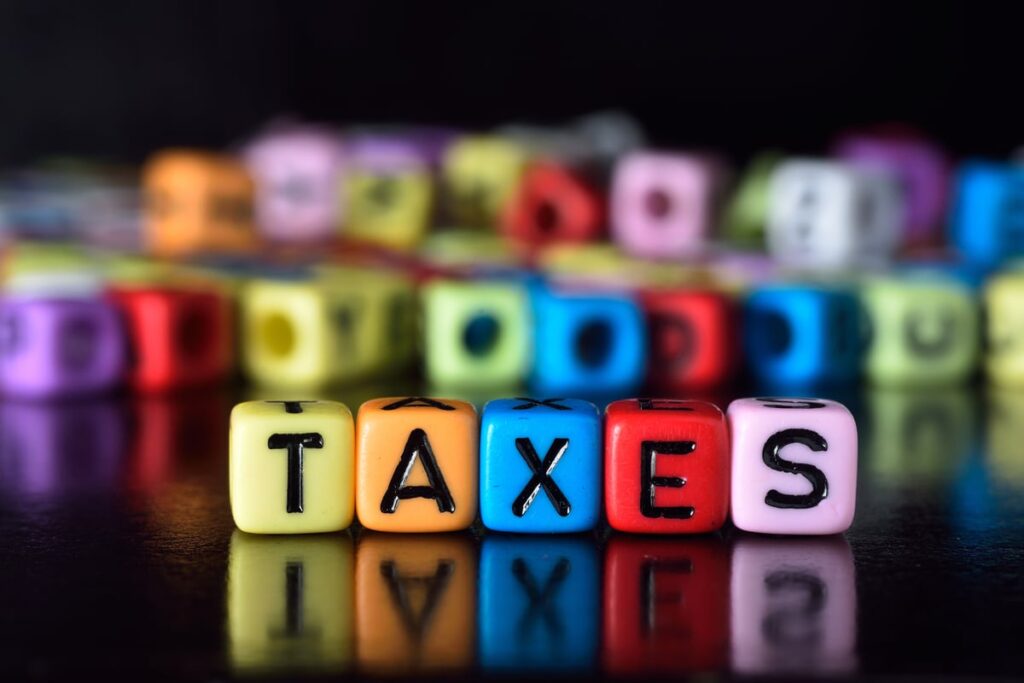 The word taxes written across five letter beads.