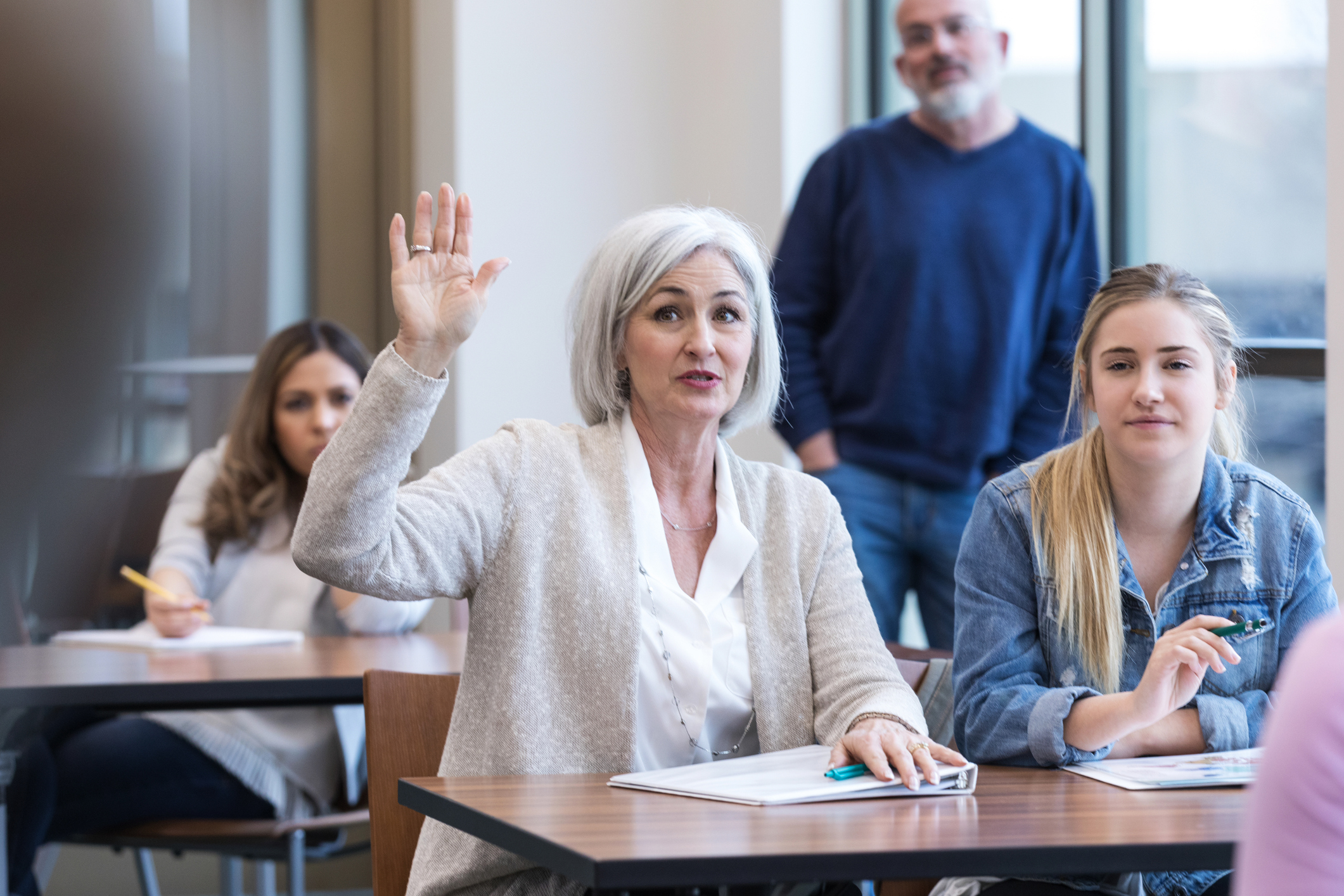 Mature woman raises her hand to ask a question during a class.