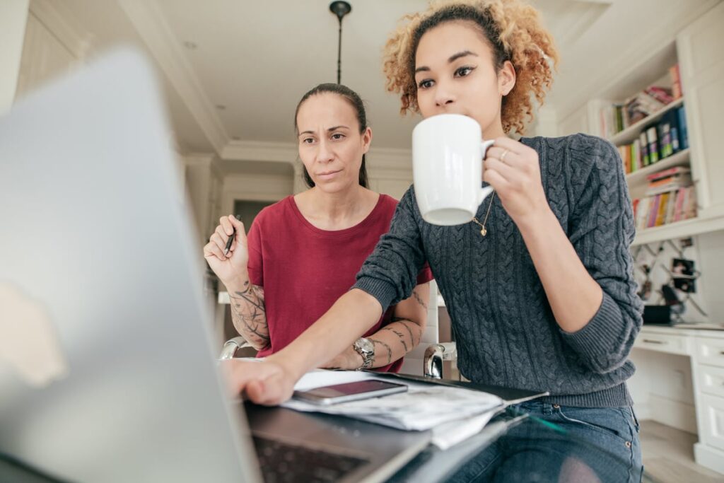 Two investors at home look at something on a computer screen.