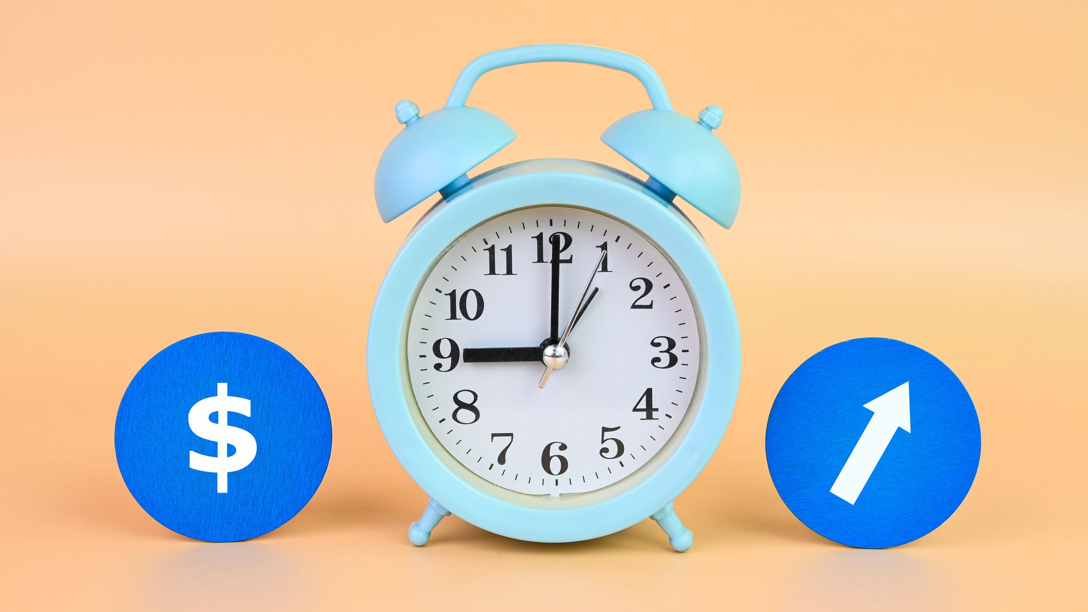 An alarm clock in the center of two blue circles with a money sign and arrow on them.