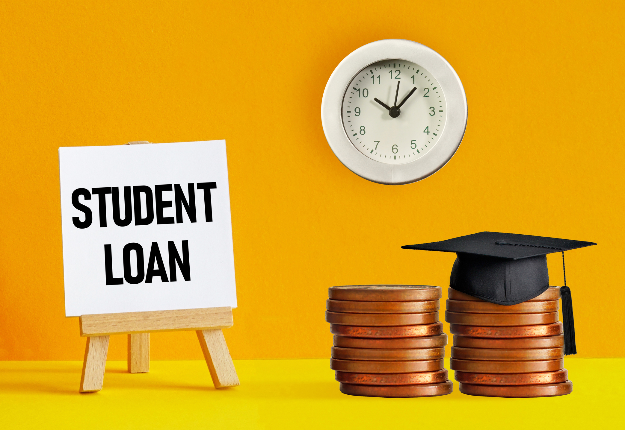 two stacks of coins with a graduation cap, clock, and the words "student loan" on a split yellow background