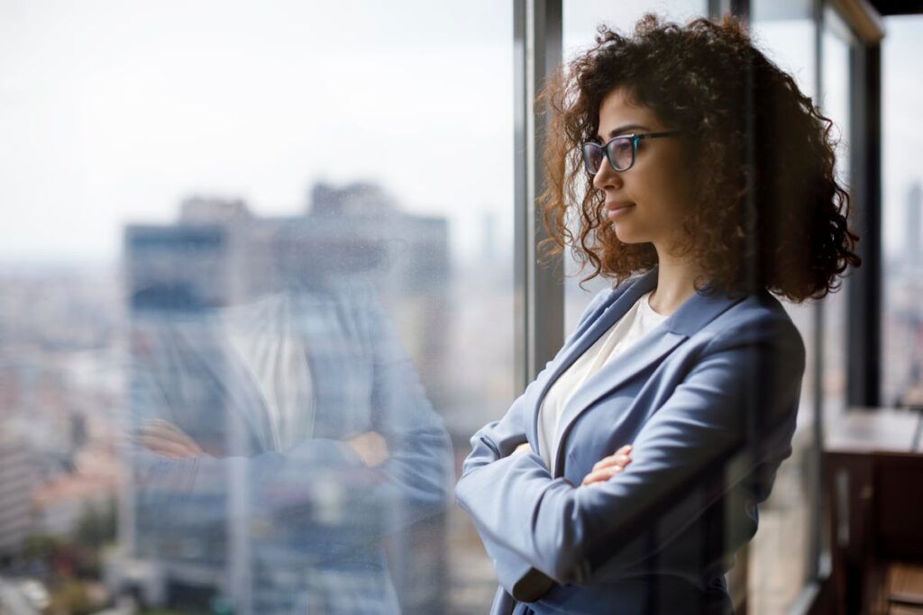 An investor looks out the window of a building in a city.