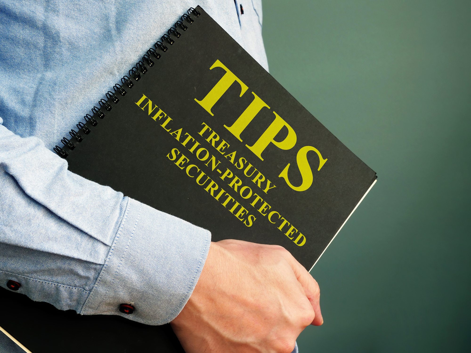 man holding a black notebook that says "Treasury-Inflation Protected Securities," and "TIPS"