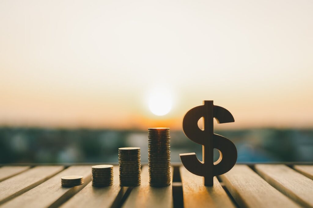Coins next to a dollar sign with a sunset in the back.