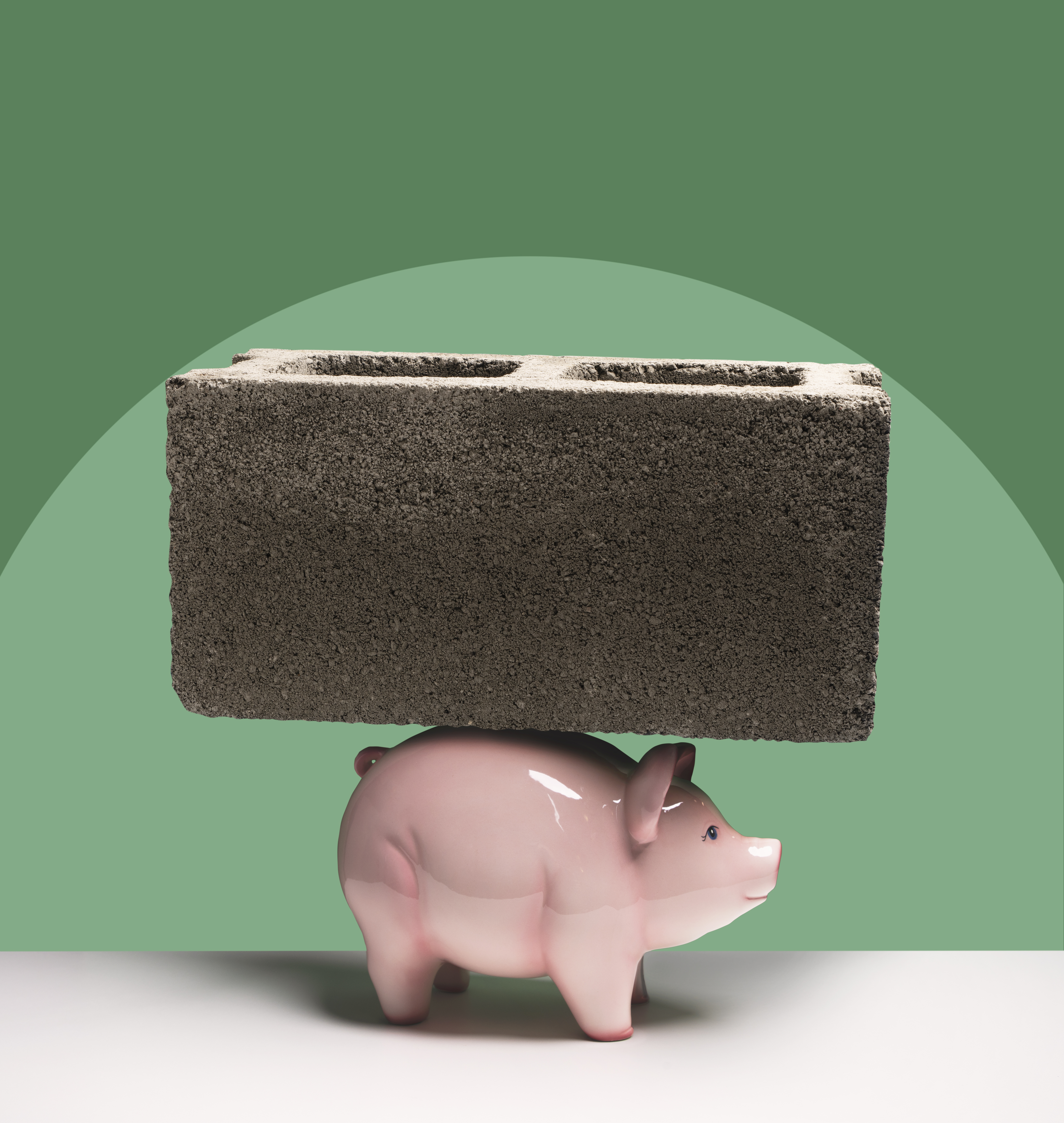 A ceramic piggy bank with a large cinder block sitting on top of it.