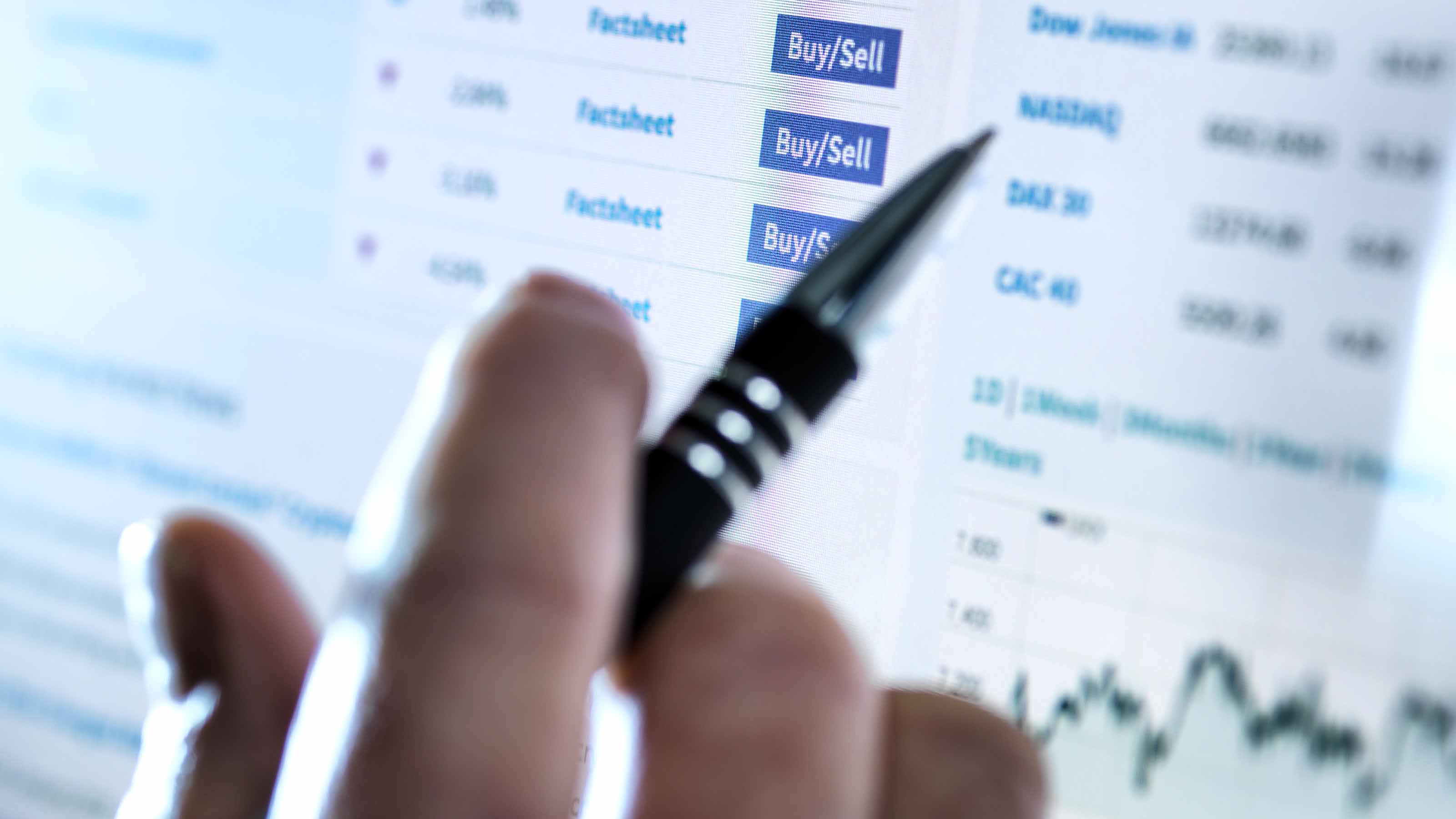 closeup of person with pen buying and selling stocks online