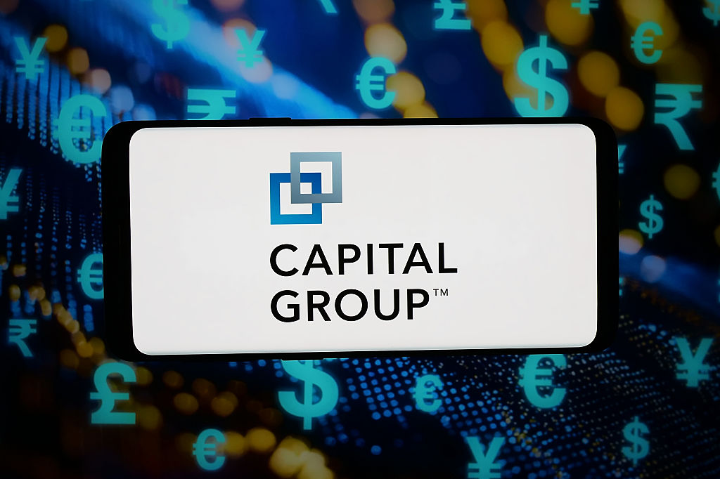 Capital Group logo displayed on a smartphone in front of abstract background on computer screen.