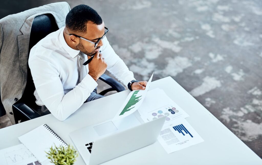 An investment analyst is sitting at a desk while reviewing a document.