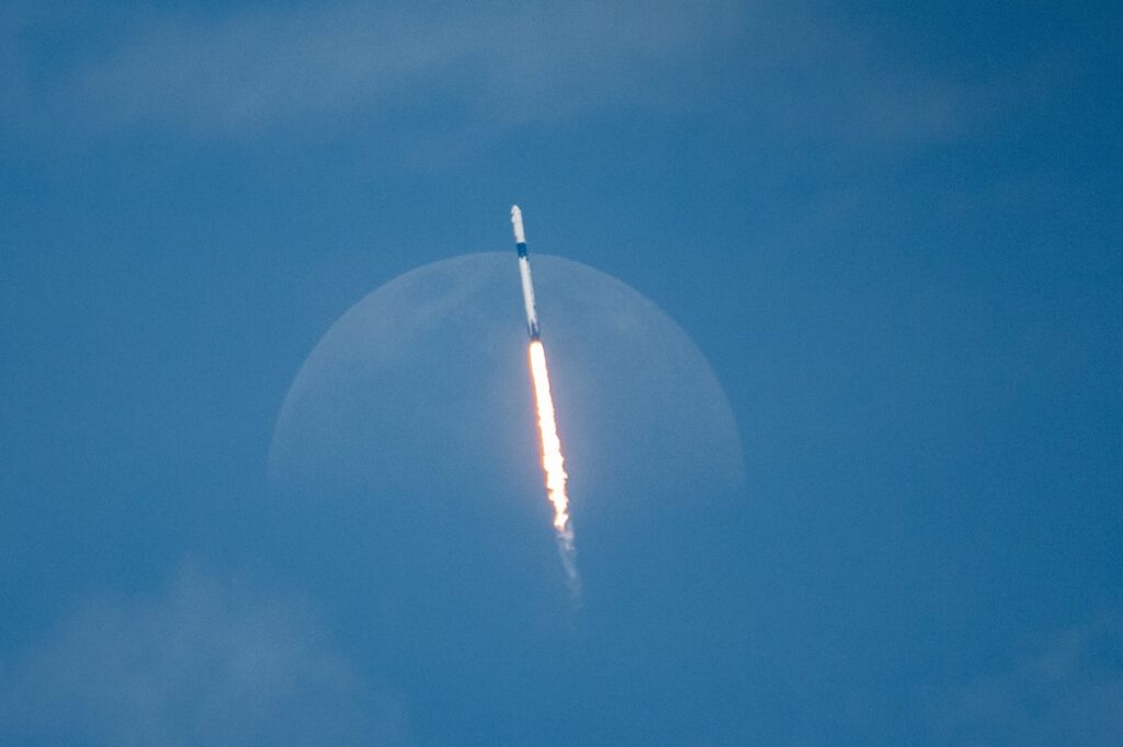 A rocket shoots into a blue sky and into space.