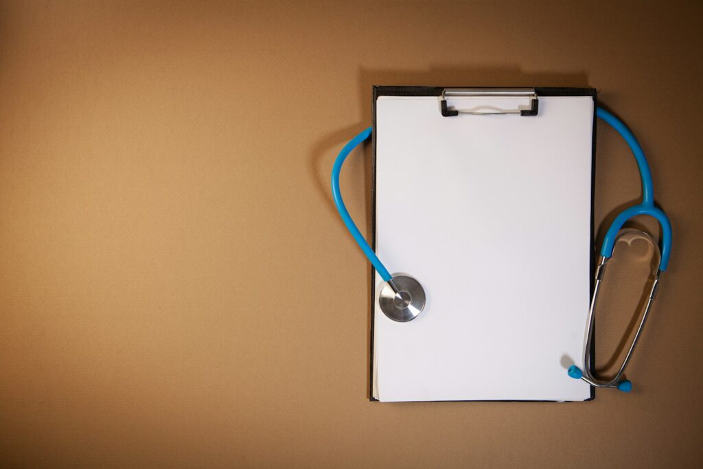Clipboard with stethoscope on a brown background; health insurance agent