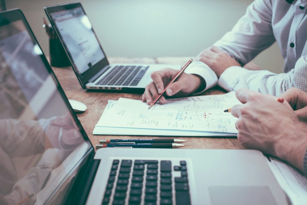person holding pencil near laptop computer; outsource your accounting