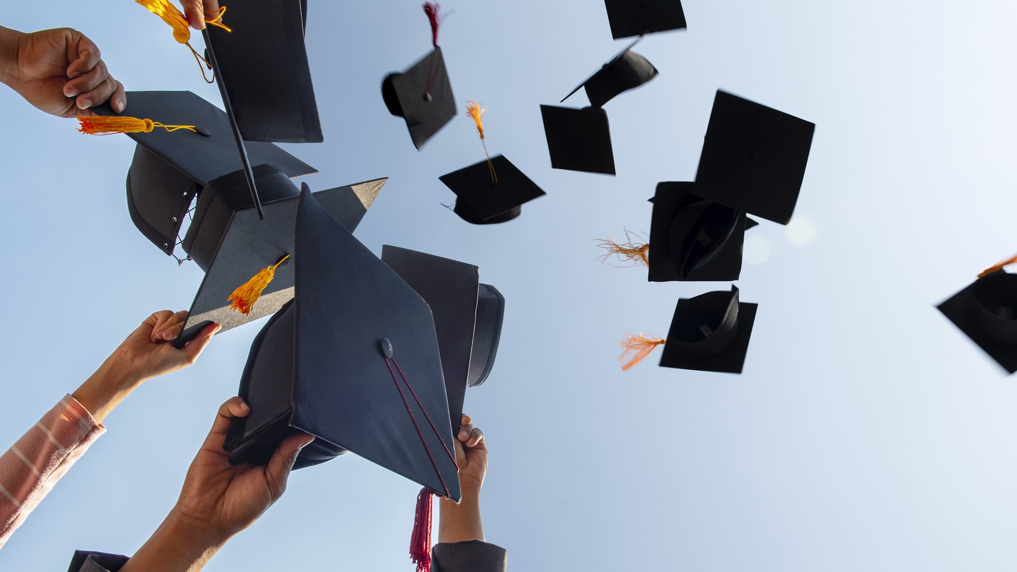 Graduates throw their mortar boards in the air.