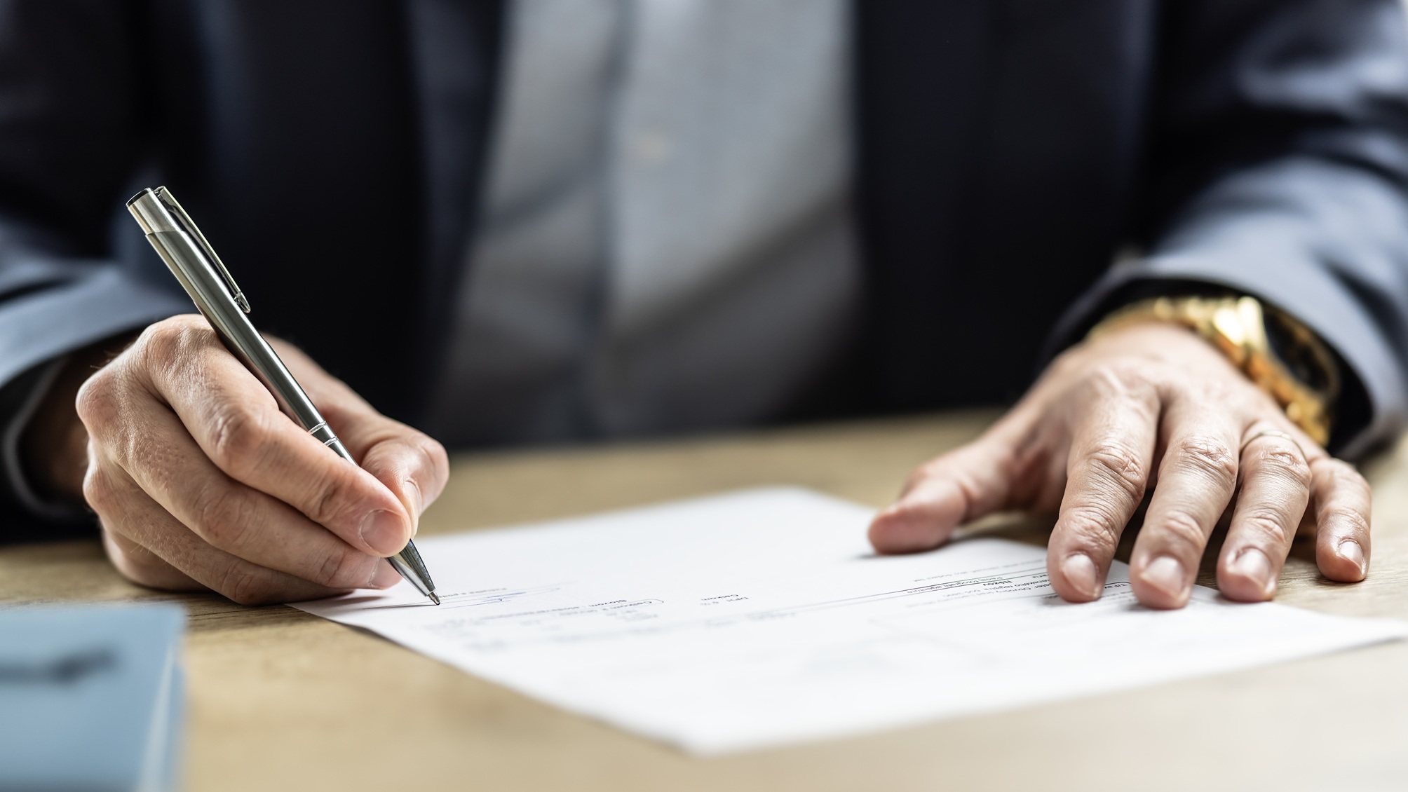 Only a businessman's hands show as he signs a document.