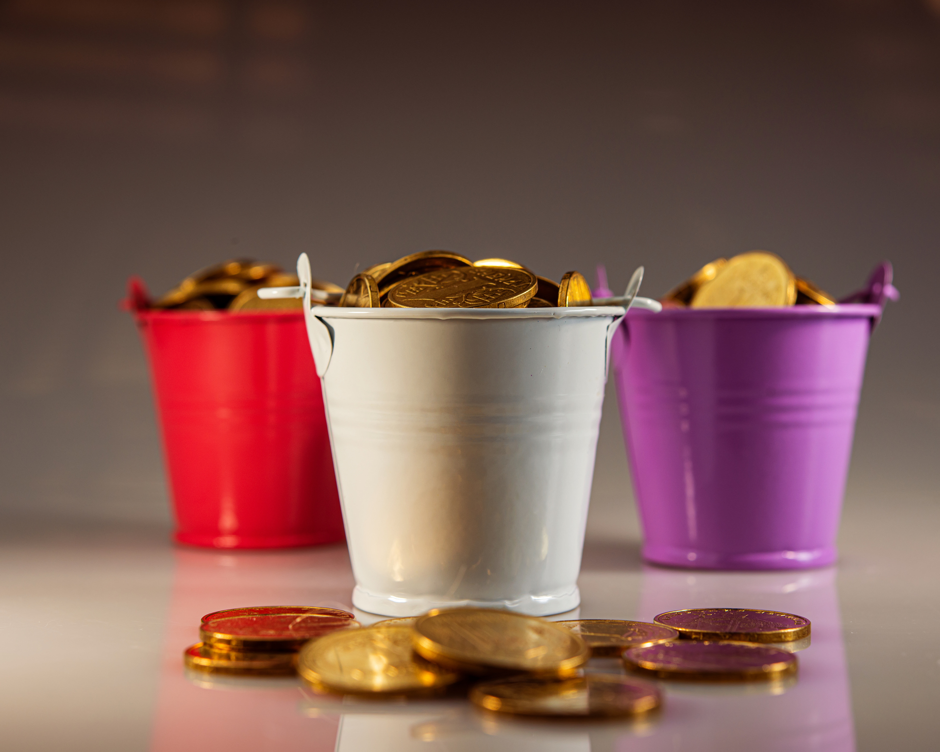 a red bucket, a purple bucket and a gray bucket filled with gold coins