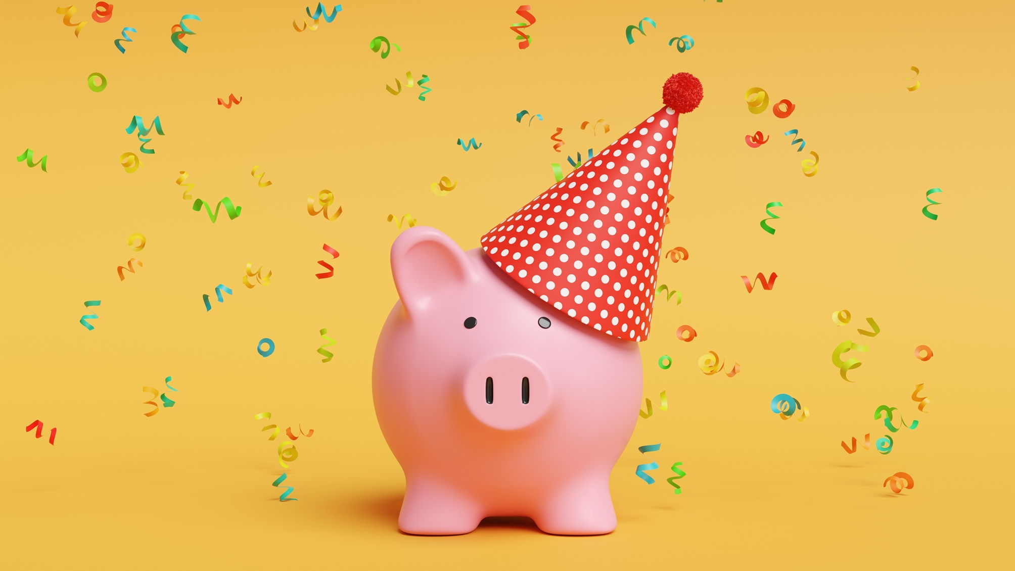 Confetti falling on a piggy bank wearing a party hat.