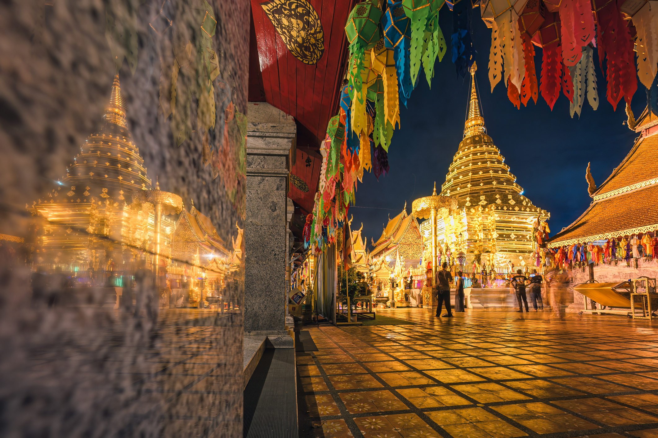 Chiang Mai, Thailand - Nov 17 2024 : Golden pagoda in Wat Phra That Doi Suthep temple illuminated with colorful lanterns and tourists visiting to worship at night