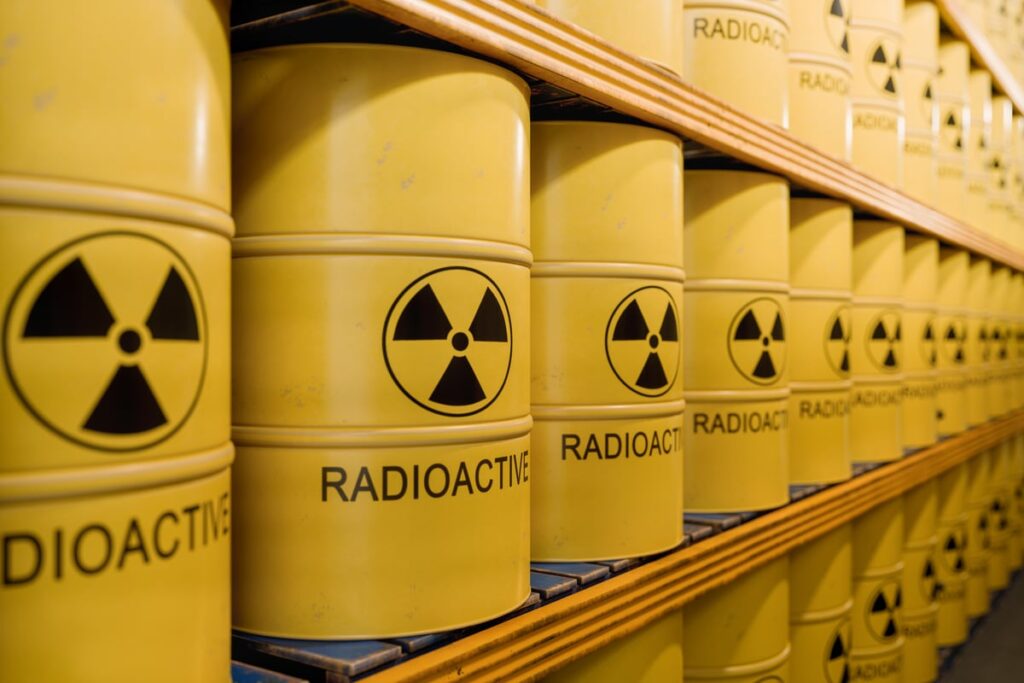 The basement of a nuclear facility with barrels that have radioactive written on them sitting on shelves.