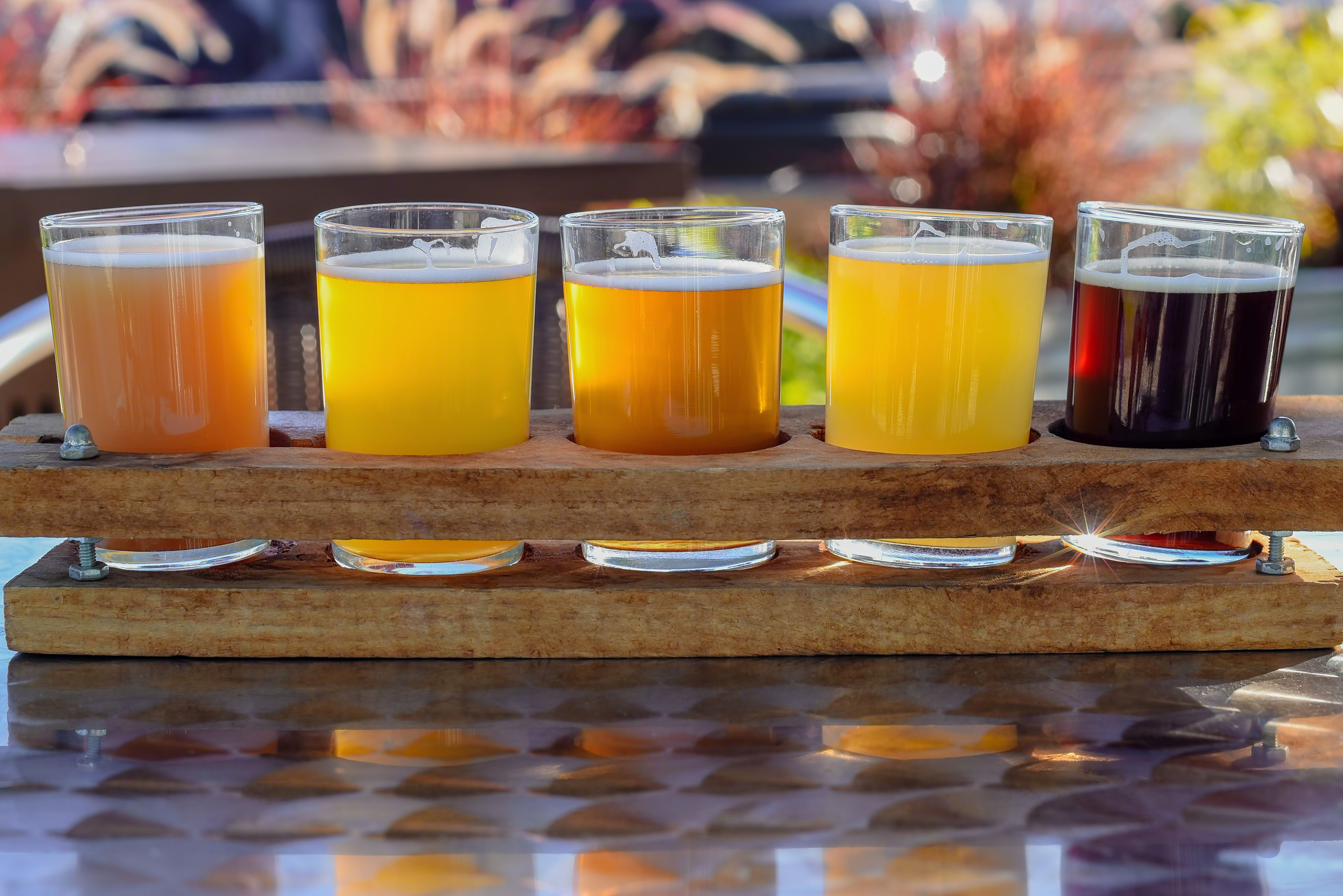 Close-up of 5 glasses of beer in the sunlight at an outdoor beer garden.