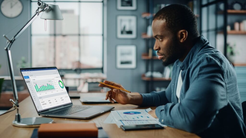 A person seated at a desk is using a laptop.
