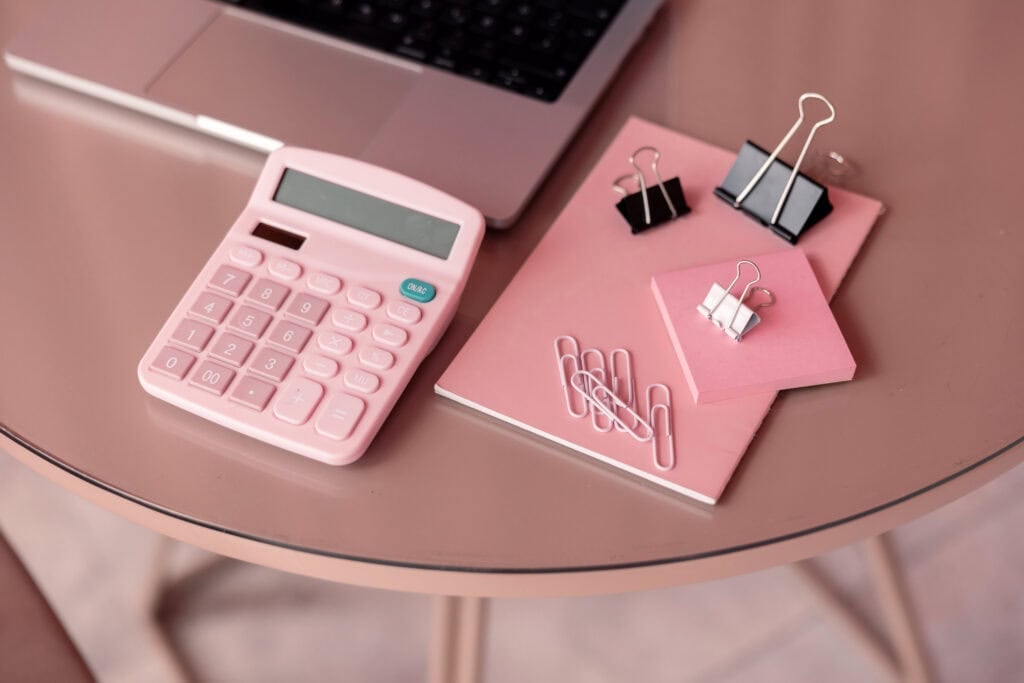 pink calculator and notebook on table
