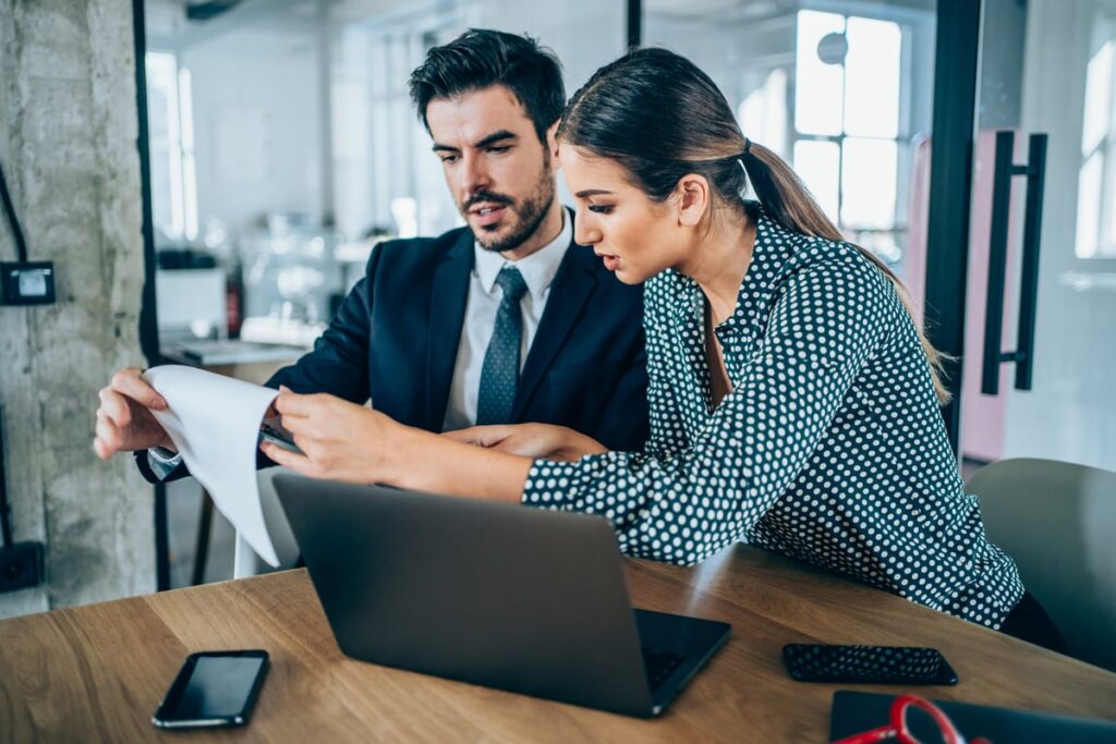 Two investors study something on a notepad.