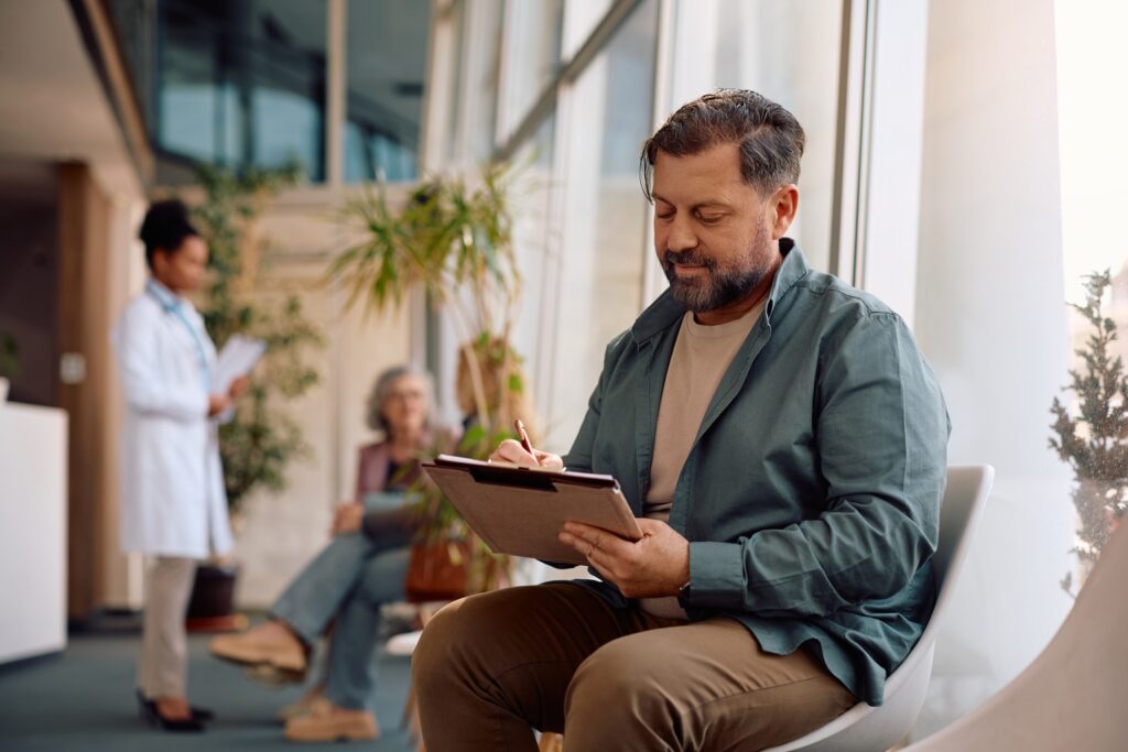 Mature man filling out paperwork before doctor